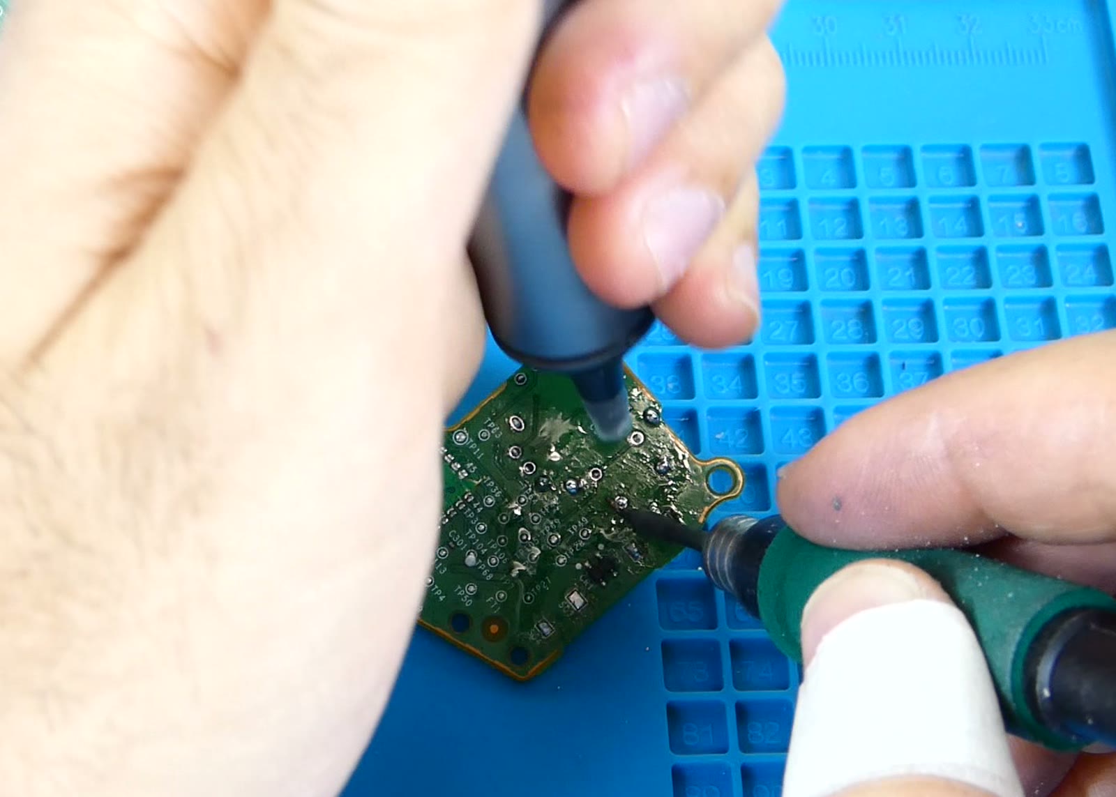 Placa de circuito con exceso de flux residual sin limpiar, mostrando una capa blanquecina pegajosa alrededor de varios puntos de soldadura